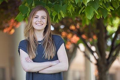 Student smiling in front of a tree